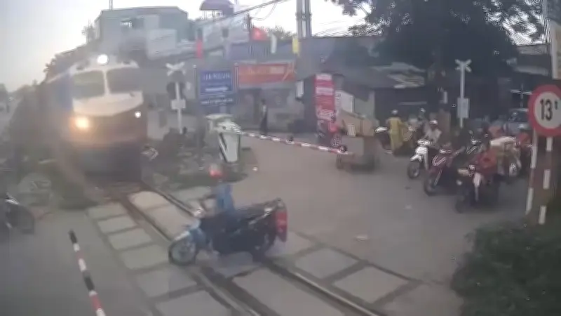 Vietnam: Zug streift Roller - Fahrer sucht erst sein Handy nach Beinahe-Unfall