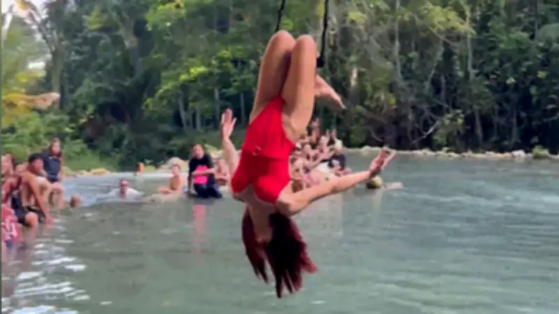 Touristin schwebt kopfüber über Lagune an Philippinen-Wasserfällen