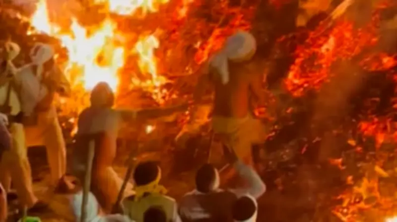 Hindu-Priester läuft barfuß über glühendes Feuer bei Holika-Dahan-Ritual